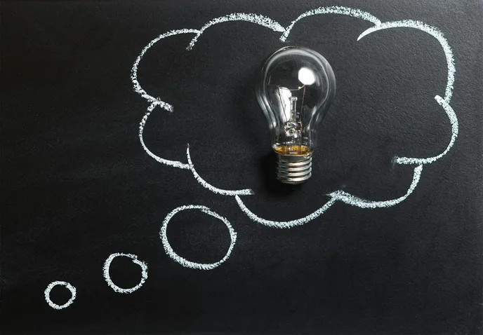 A light bulb surrounded by a thought bubble drawn in chalk on a blackboard, symbolizing inspiration and ideas.
