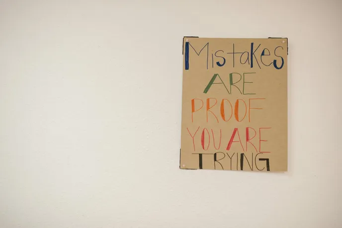 A motivational poster that reads 'Mistakes ARE PROOF YOU ARE TRYING' in colorful letters on a brown background.